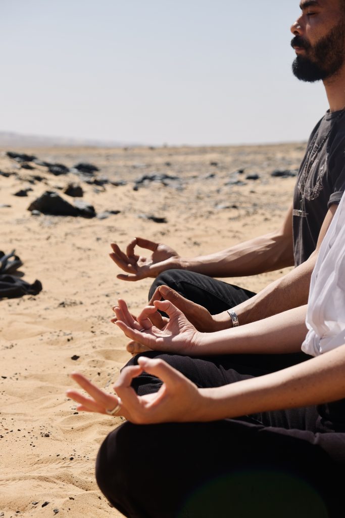 the hands of meditators in mudra poses, sit on the desert of Egypt